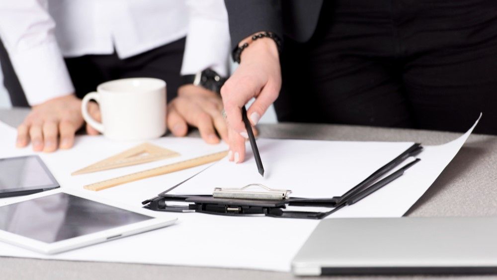 close-up-businesswoman-s-hand-holding-pencil-paper-clipboard-desk.jpg